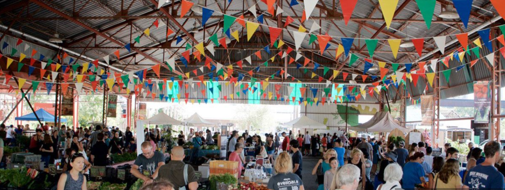 Outdoor Farmers Market with many visitors buying fresh produce and