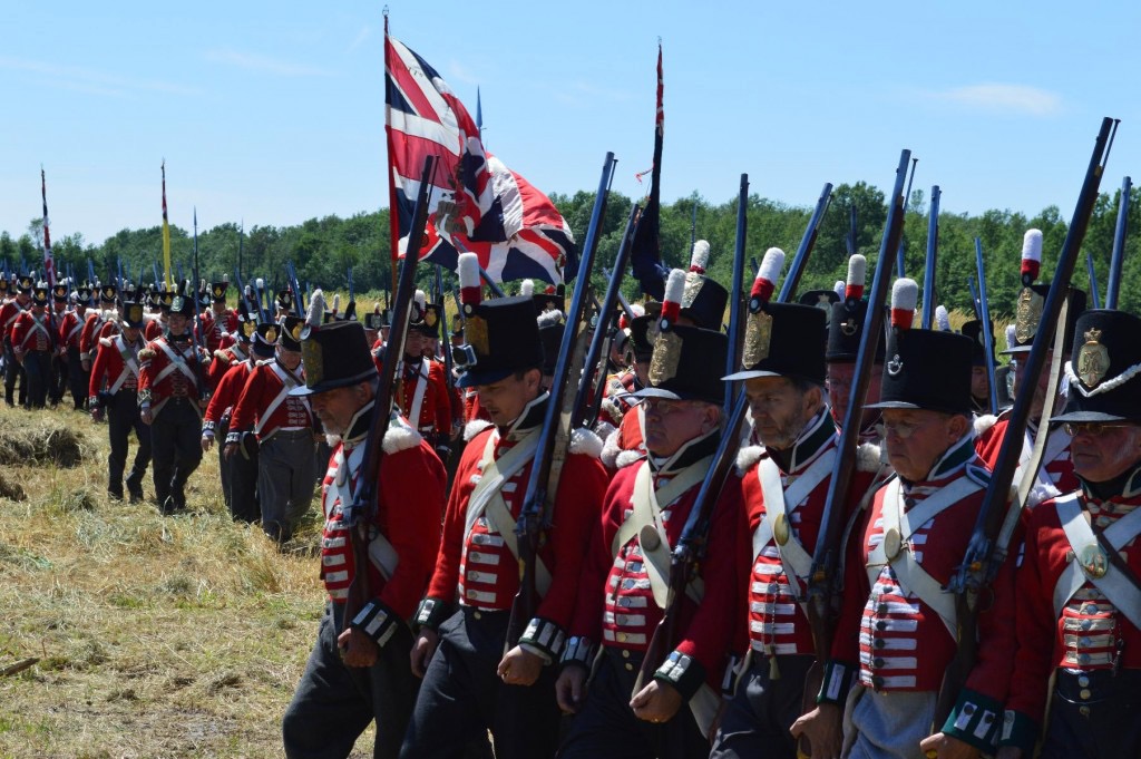 a reenactment of many soldiers in redcoats marching to battle in a field