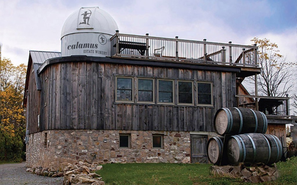 outdoor shot of Calamus winery with barrels out front and old barn and telescope