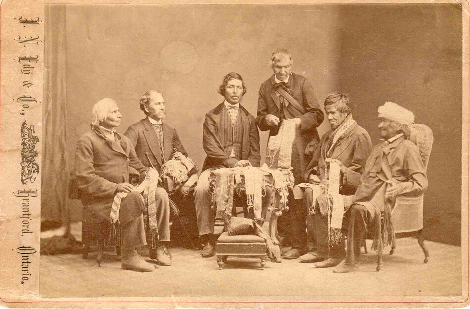 photo from 1871 of  6 Indigenous chiefs sharing wampum belts that are used to signify peace and important treaty agreements