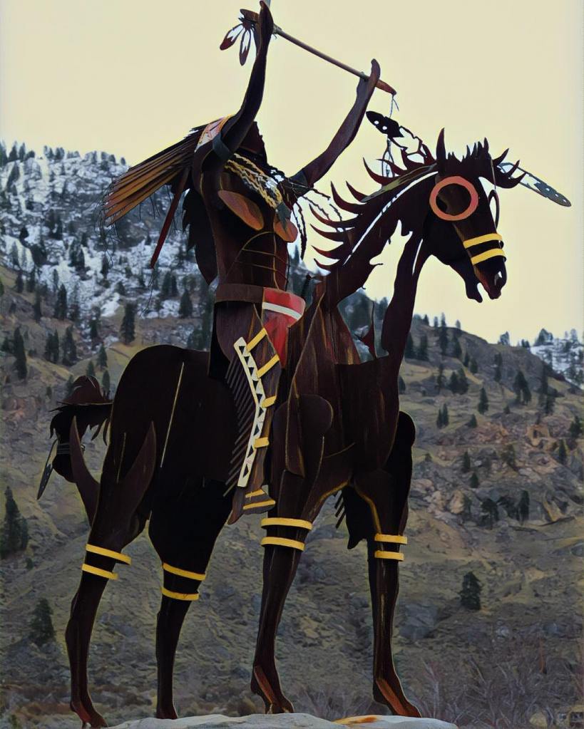 metal art sculpture of Indian chief with headdress on horse against mountain backdrop