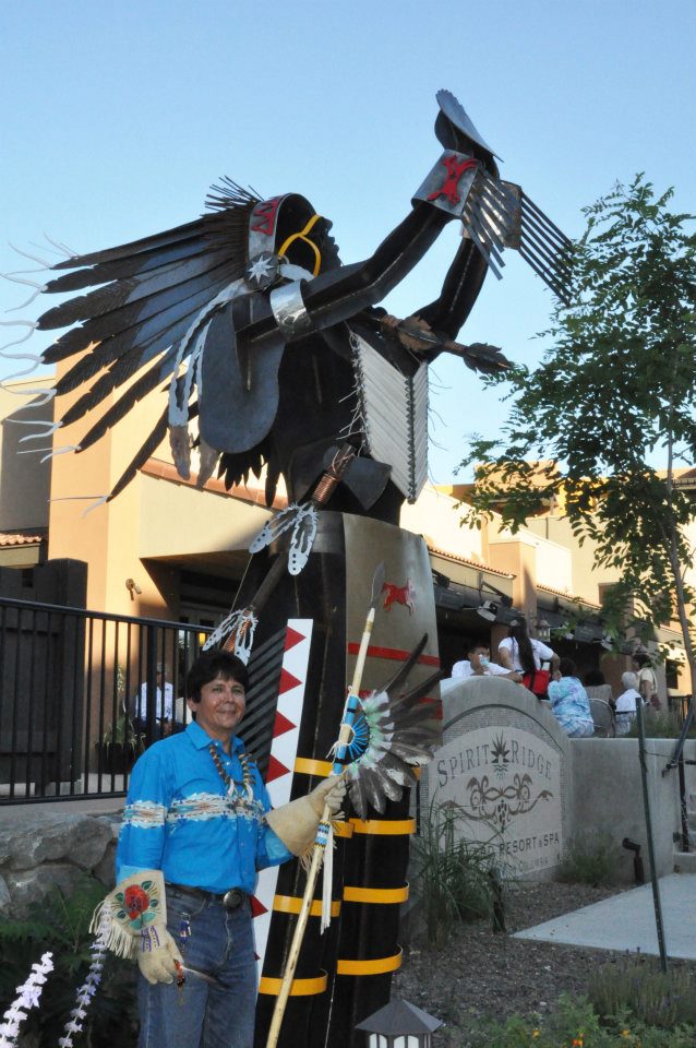 Chief Louis outside of hotel framed by Chief metal sculpture